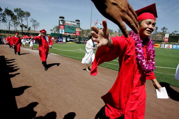 A+graduate+gets+a+high+five+from+a+friend+in+the+stands+during+the+processional+of+the+Elsinore+High+School+graduation+ceremony+at+The+Diamond+in+Lake+Elsinore%2C+CA.+Wednesday%2C+June+1%2C+2016.