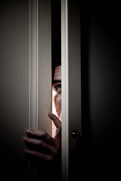 Man hiding in a closet spying from the slit.